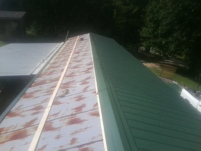 Old rusted panels beside newly installed green metal roofing — Wind Damage Roof Repair by Roofing Brothers in Dane