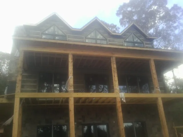 Dormers and porch framing on a large log home under construction — Roof Coating work by our crew in Dane