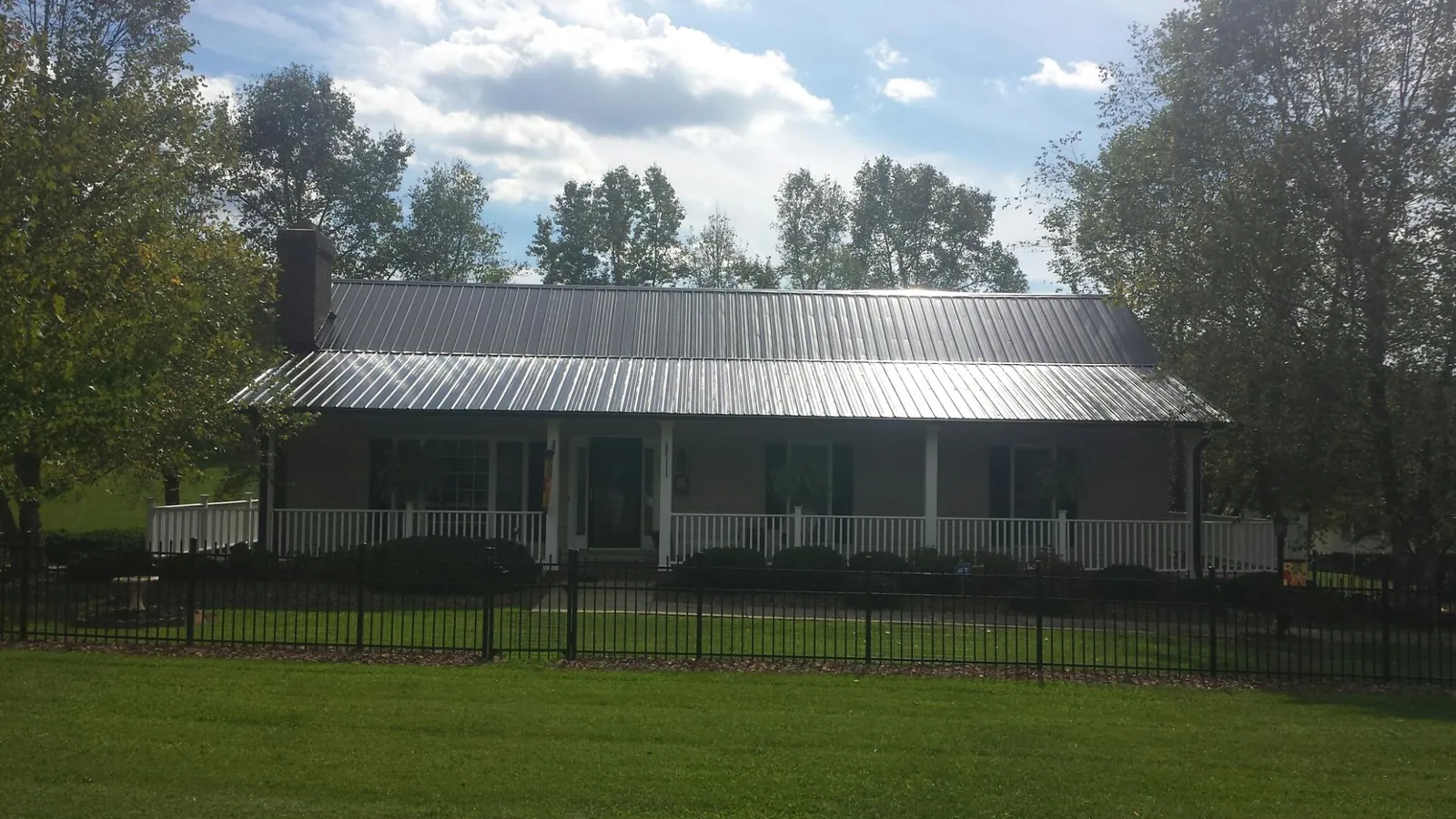 Gray metal roof on a brick ranch with a full width front porch — Gutter Guard Installation work by our crew in Dane