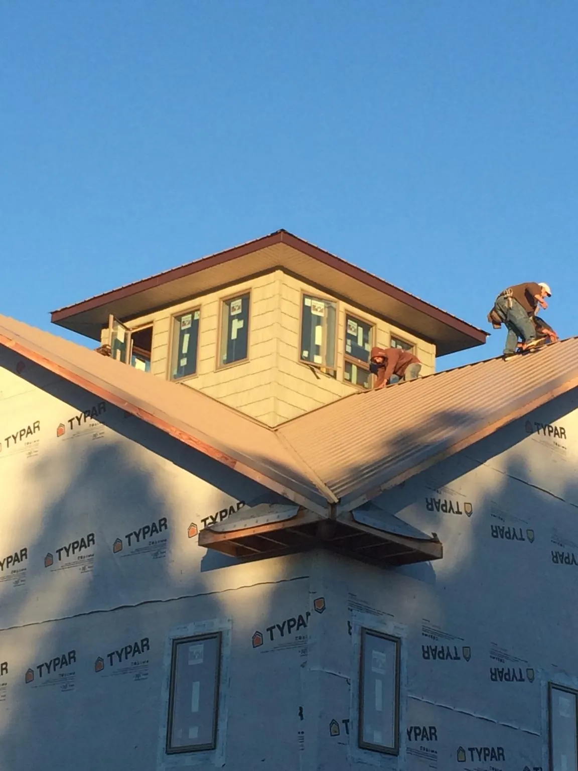 Roofers working around a rooftop cupola on a new metal roof at sunset — Roof Waterproofing in Dane by Roofing Brothers